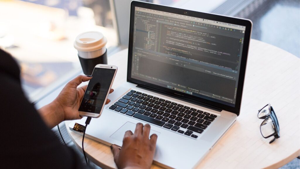Frau am Handy und Laptop coding